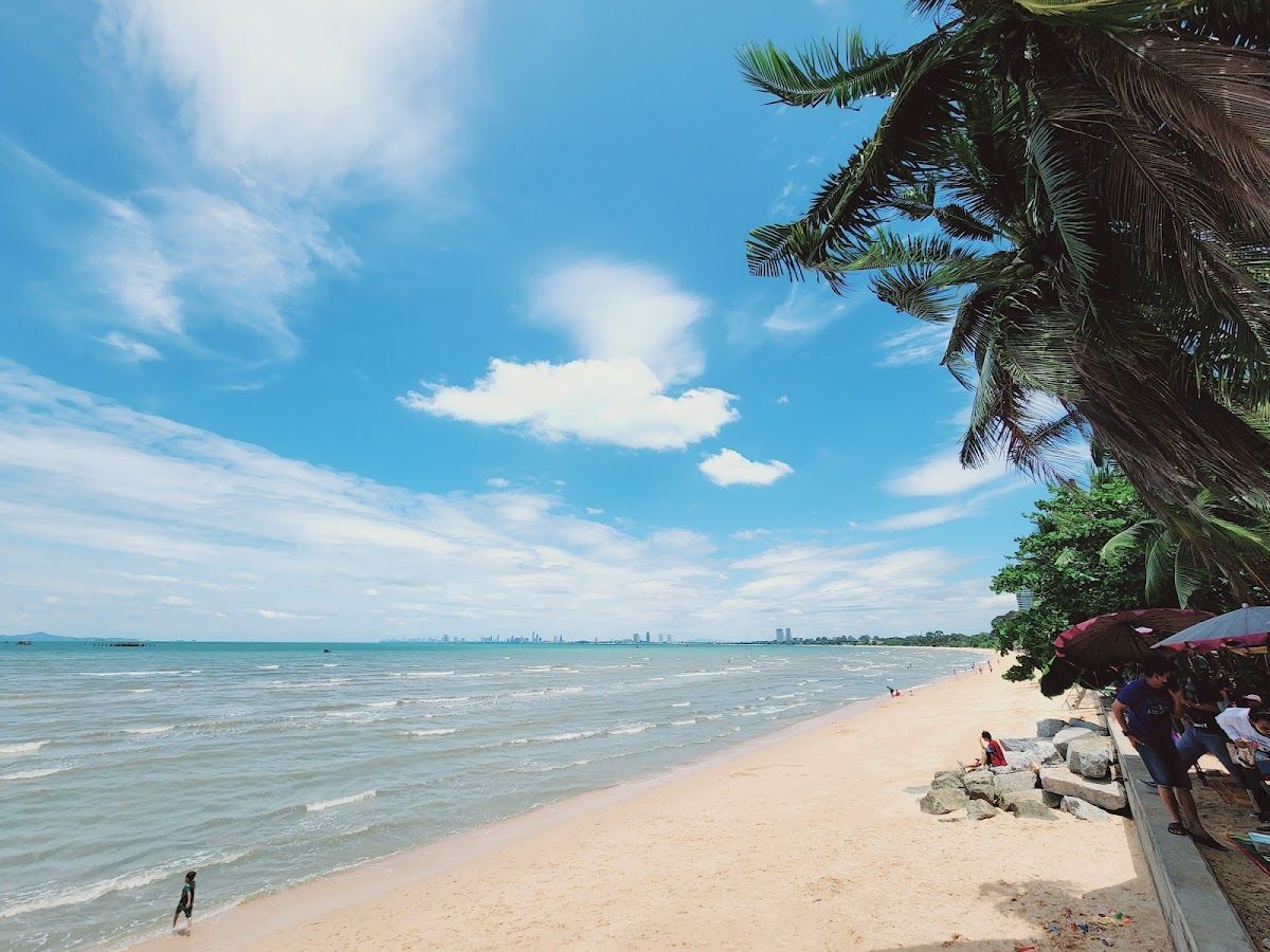 Ban Amphur Beach — wide sandy beach lined with coconut palms at dusk, calm water, and hills across the bay