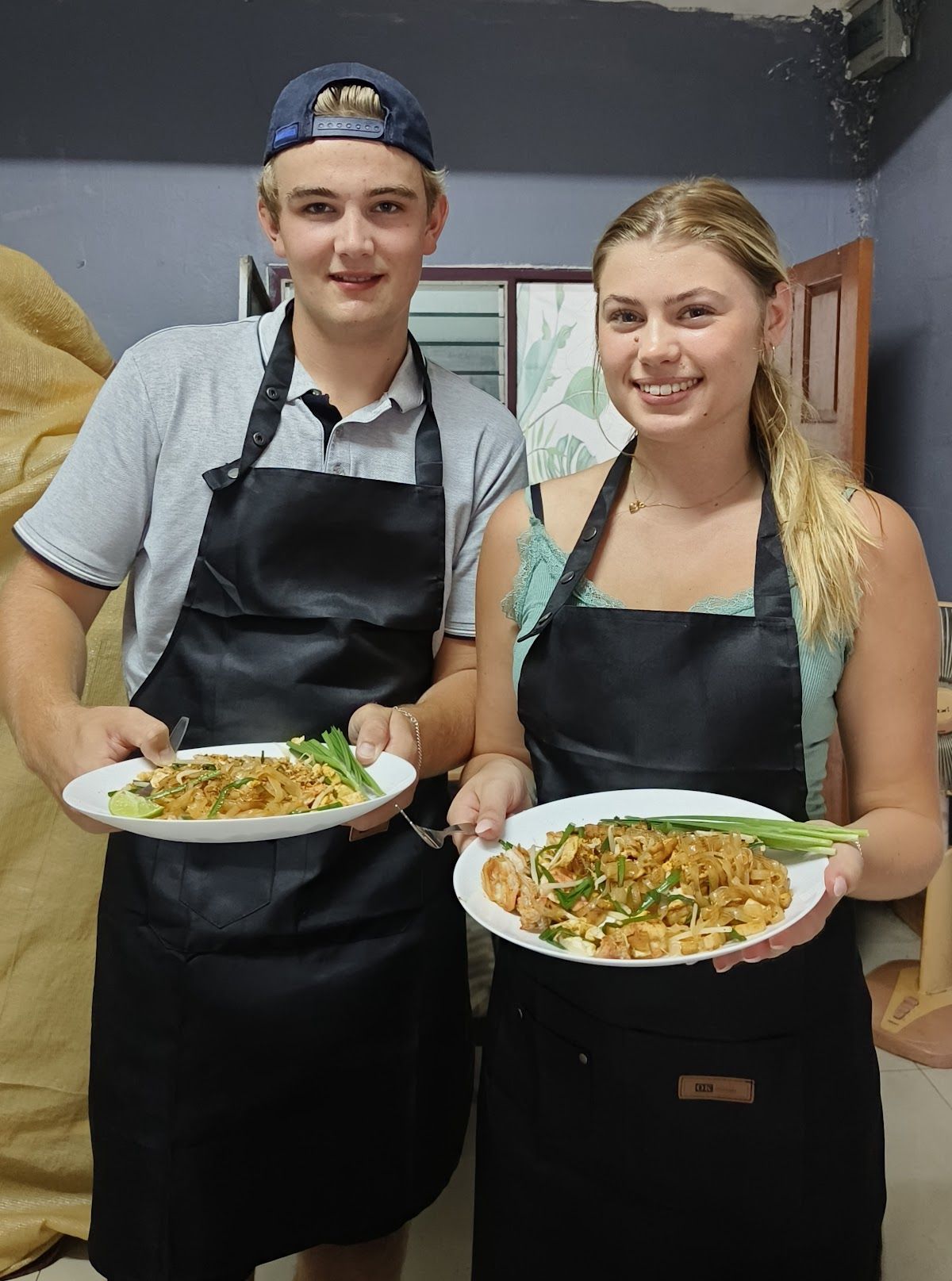 Small group of travellers eating their homemade Thai dishes at the end of a cooking class, including curry and pad thai