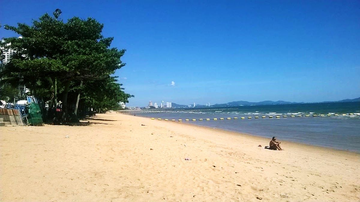 Jomtien Beach wide sandy shoreline with calm Gulf water and Pattaya city skyline visible in the distance