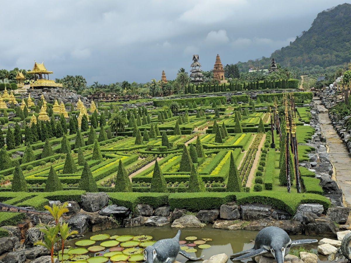 Elephants performing at Nong Nooch's outdoor elephant arena, with trainers and lush tropical backdrop