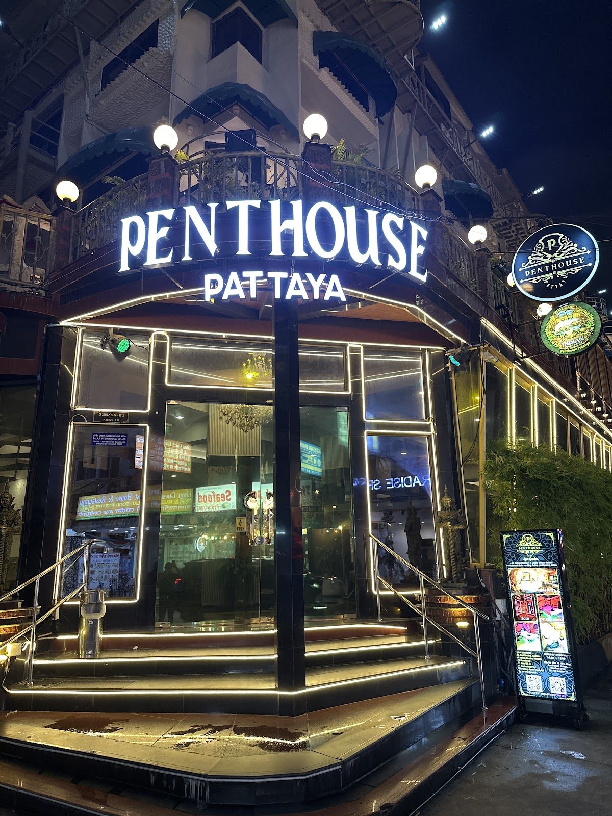 Penthouse Pattaya hotel exterior at night — the illuminated Penthouse Pattaya neon sign and glass entrance on Beach Road
